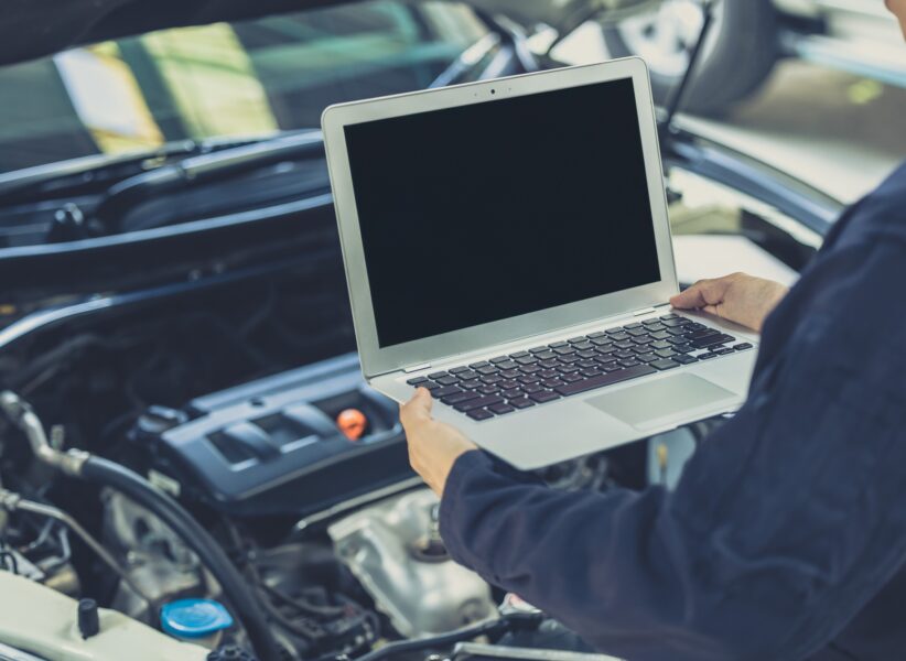 laptop computer blank screen with modern car engine performance ECU tune up in auto garage workshop