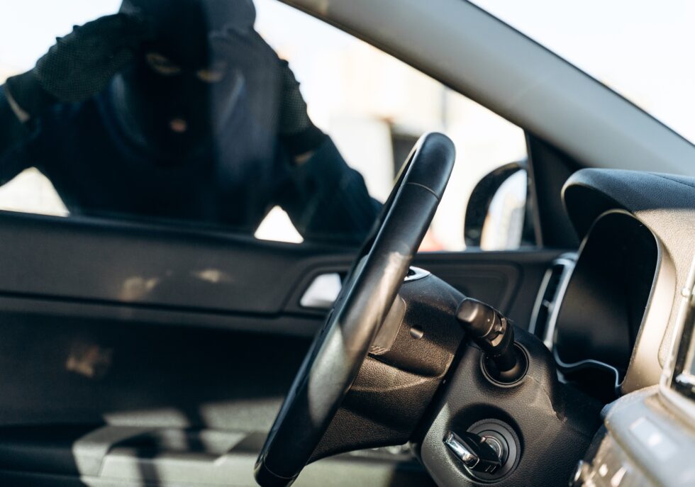 View from the car at the man dressed in black with a balaclava looking at the glass of car